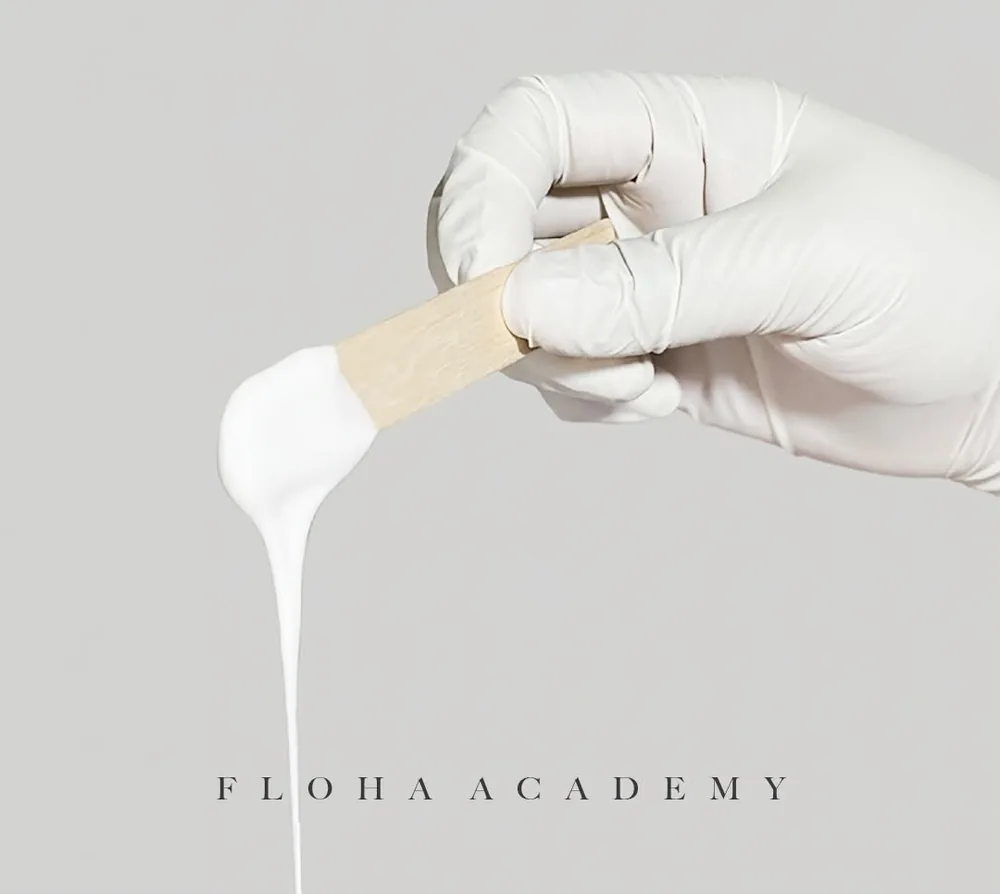 FLOHA ACADEMY, 장갑 낀 손에 든 스패출러에서 흰 왁스가 흘러내리는 모습
